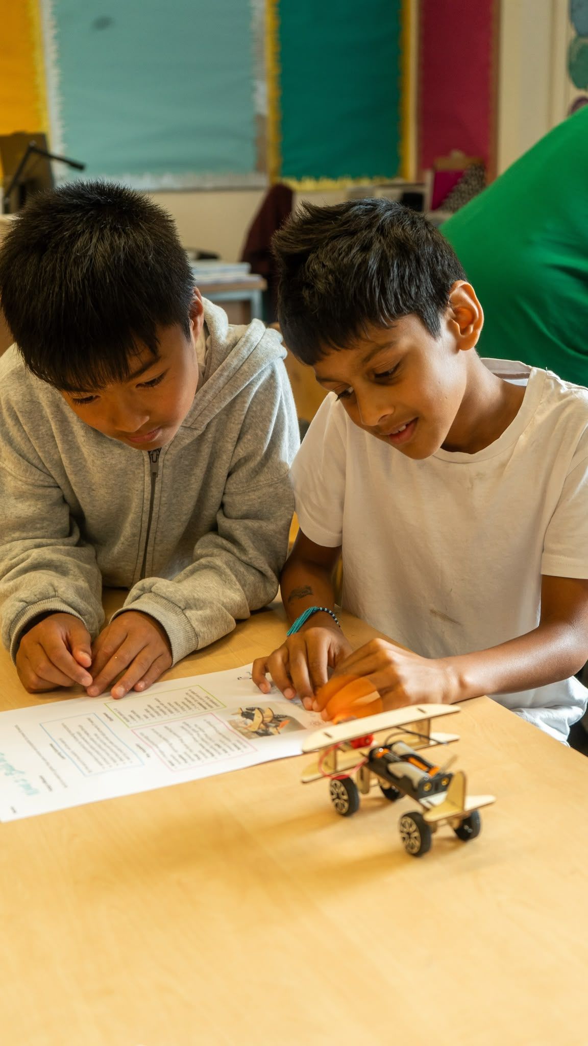 Two boys building a wooden model together